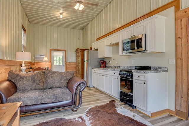 kitchen featuring white cabinets, white refrigerator, light hardwood / wood-style flooring, and black range with gas cooktop