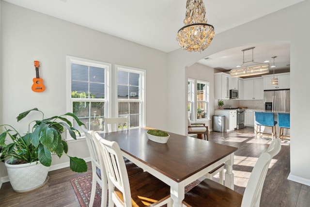 1606 Stovall Ct, Johns Island, SC 29455 - dining room with an inviting chandelier, baseboards, dark wood-style floors, and arched walkways