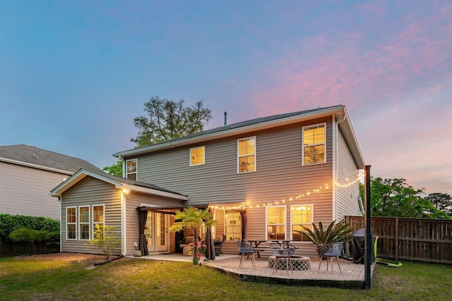 1606 Stovall Ct, Johns Island, SC 29455 - back of house at dusk featuring a lawn, fence, and a patio area