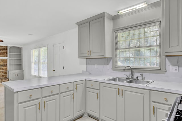 kitchen with kitchen peninsula, brick wall, a healthy amount of sunlight, and sink