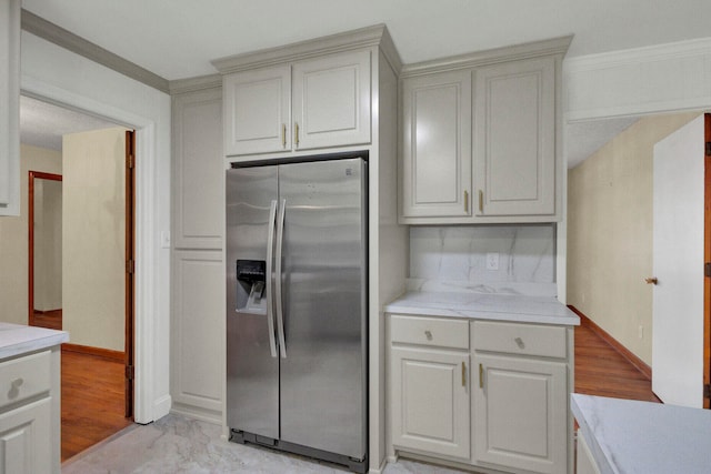 kitchen featuring white cabinets, light wood-type flooring, stainless steel fridge, and ornamental molding