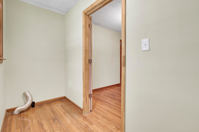 hall with light hardwood / wood-style floors and a textured ceiling