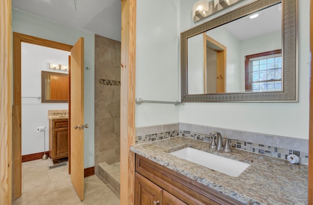 bathroom featuring vanity, a tile shower, and tile patterned floors