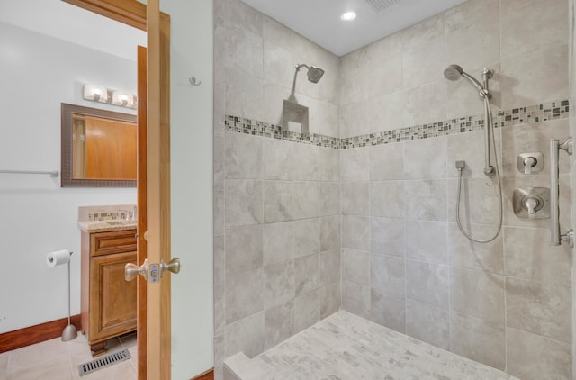 bathroom with vanity, tile patterned flooring, and a tile shower