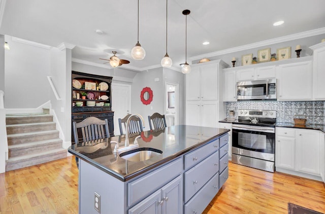 kitchen with white cabinets, a sink, dark countertops, and appliances with stainless steel finishes