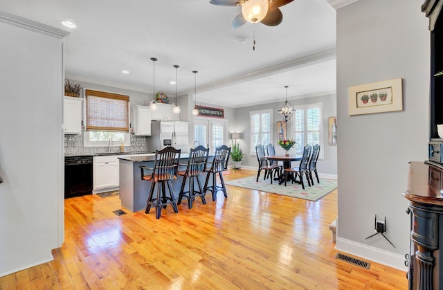 kitchen featuring stainless steel fridge, black dishwasher, white cabinetry, ceiling fan with notable chandelier, and a breakfast bar area