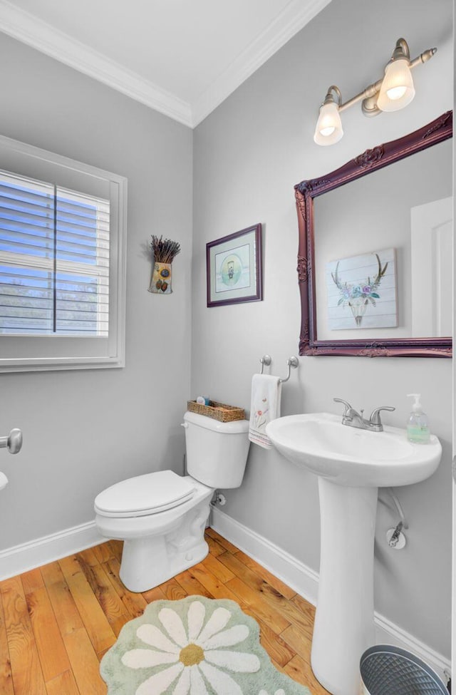bathroom featuring baseboards, toilet, ornamental molding, and hardwood / wood-style floors