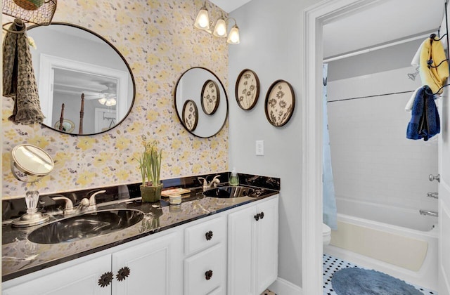 bathroom featuring shower / bathtub combination with curtain, a sink, a ceiling fan, and wallpapered walls