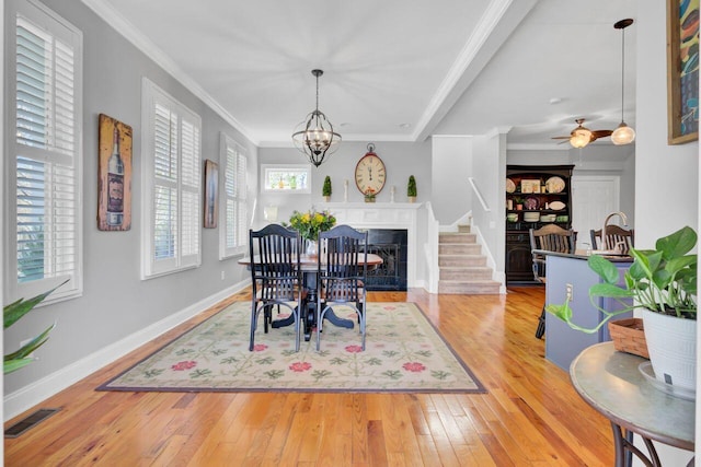 dining room featuring hardwood / wood-style floors, visible vents, baseboards, and crown molding