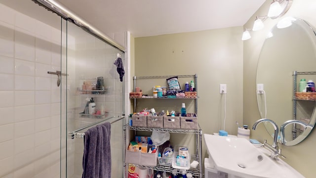 bathroom featuring a shower with door and sink