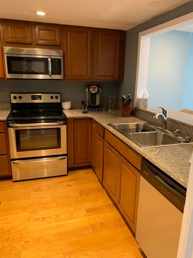 kitchen with appliances with stainless steel finishes, light hardwood / wood-style flooring, and sink