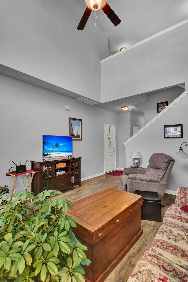 living room featuring a towering ceiling, light hardwood / wood-style flooring, and ceiling fan