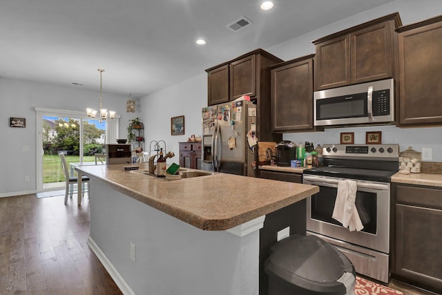 kitchen featuring pendant lighting, a kitchen island with sink, sink, stainless steel appliances, and a chandelier