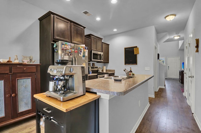 kitchen with a center island with sink, dark brown cabinetry, sink, and appliances with stainless steel finishes