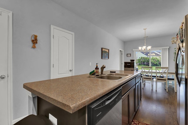 kitchen with appliances with stainless steel finishes, dark wood-type flooring, a center island with sink, a notable chandelier, and hanging light fixtures