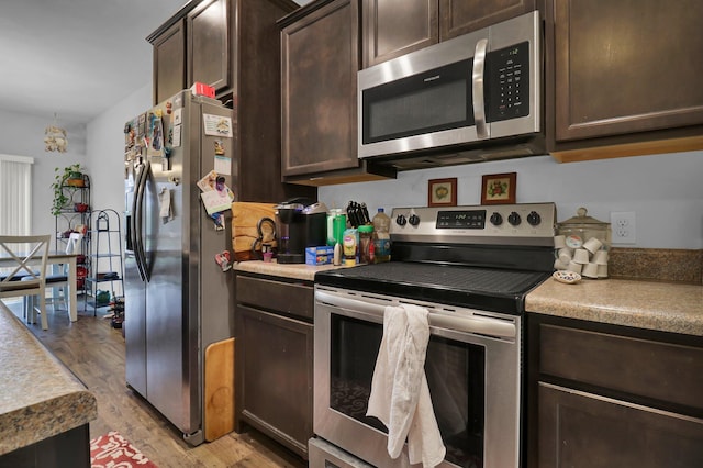 kitchen with dark brown cabinetry, stainless steel appliances, and light hardwood / wood-style floors