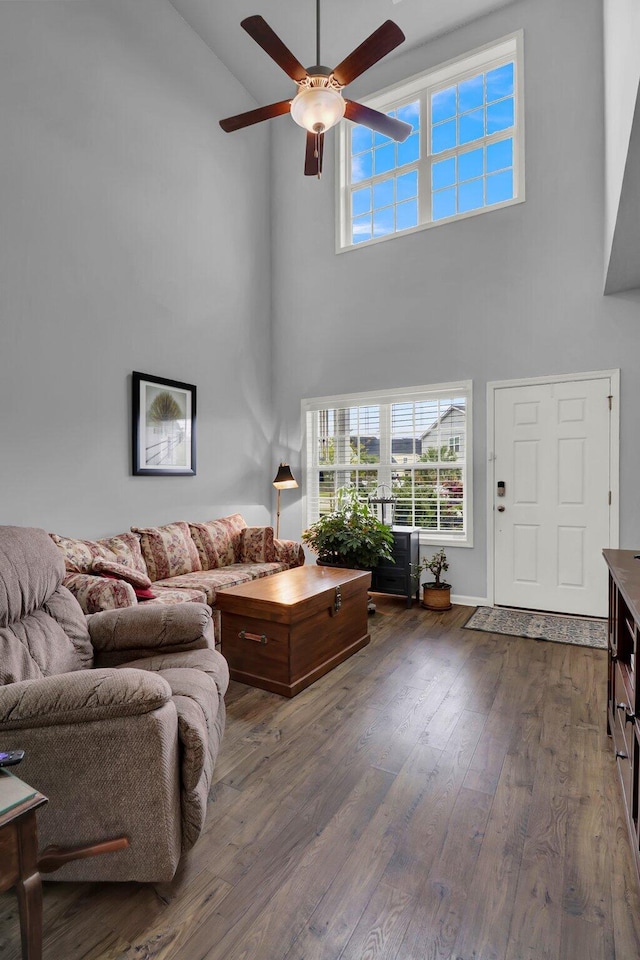 living room with a high ceiling, ceiling fan, and dark wood-type flooring