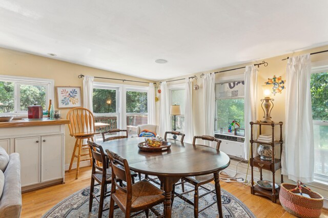 dining area with light wood-type flooring, plenty of natural light, and vaulted ceiling