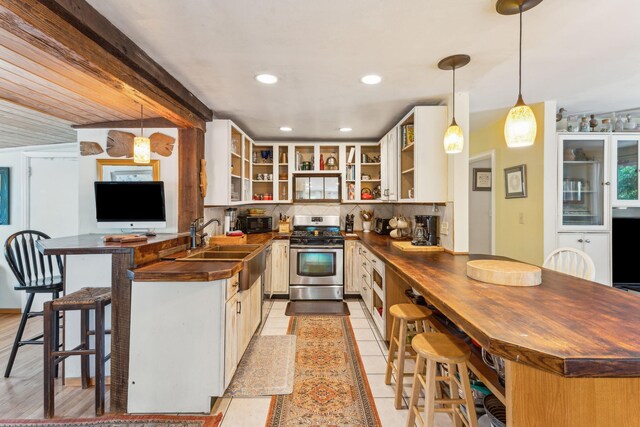 kitchen featuring stainless steel range with gas cooktop, tasteful backsplash, light hardwood / wood-style flooring, wood counters, and sink