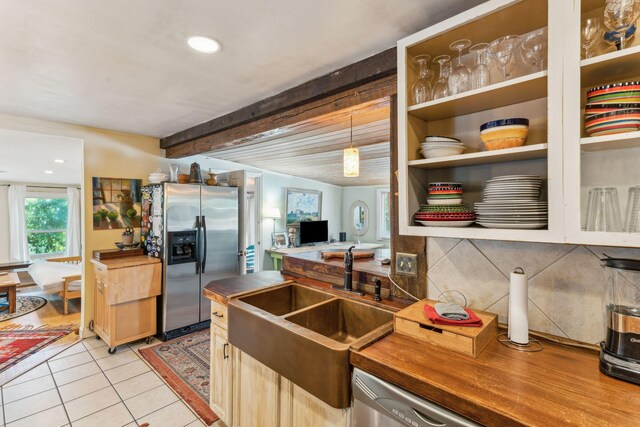 kitchen with beamed ceiling, light tile patterned floors, sink, hanging light fixtures, and appliances with stainless steel finishes