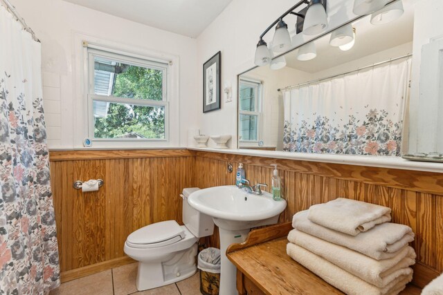 bathroom with toilet, walk in shower, tile patterned floors, and wooden walls