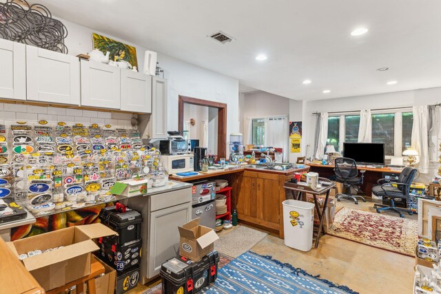 kitchen featuring built in desk, white cabinets, and tasteful backsplash