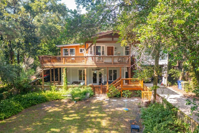 back of property featuring a wooden deck and a yard