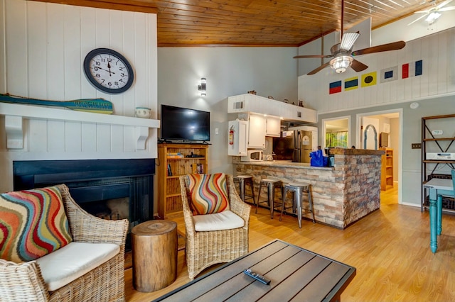 living room with wood ceiling, crown molding, high vaulted ceiling, light hardwood / wood-style flooring, and ceiling fan