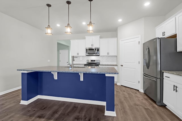 kitchen with appliances with stainless steel finishes, white cabinets, decorative light fixtures, and a sink