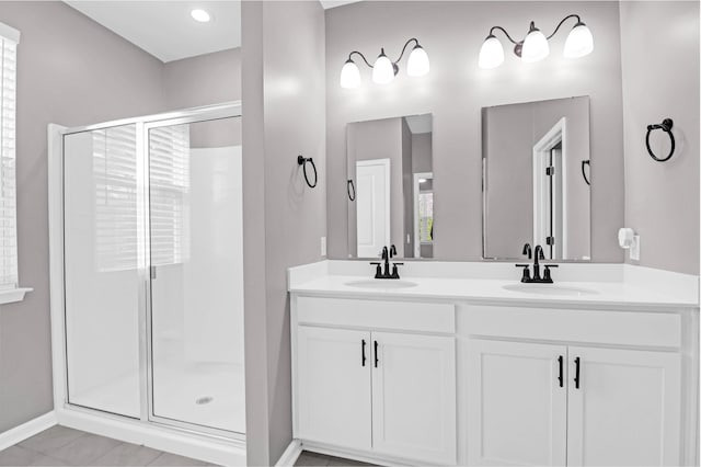 full bathroom featuring a sink, a shower stall, baseboards, and double vanity