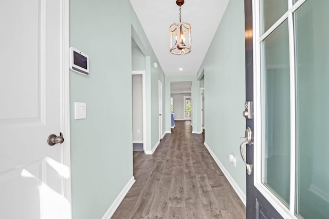 hallway with an inviting chandelier, wood finished floors, and baseboards