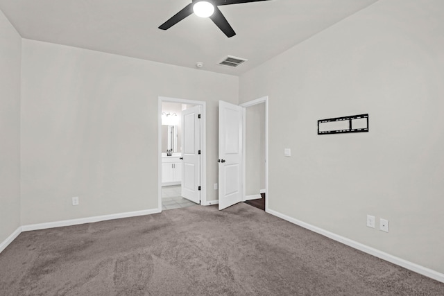 unfurnished bedroom with baseboards, visible vents, light colored carpet, ensuite bath, and ceiling fan