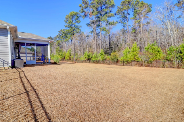 view of yard with a sunroom, a fenced backyard, and central AC