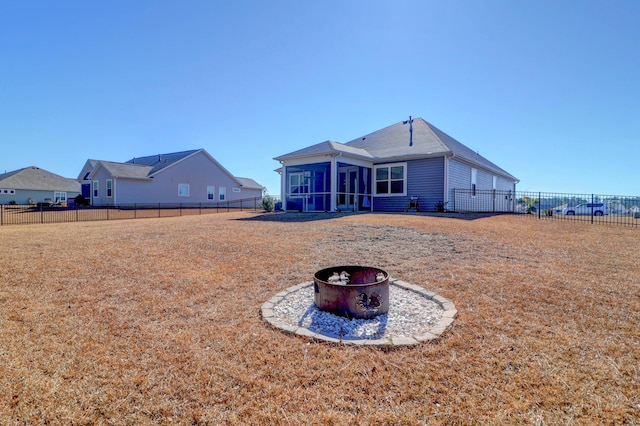 back of house featuring an outdoor fire pit, a sunroom, and a fenced backyard