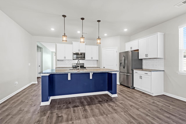 kitchen featuring stainless steel appliances, an island with sink, visible vents, and white cabinetry