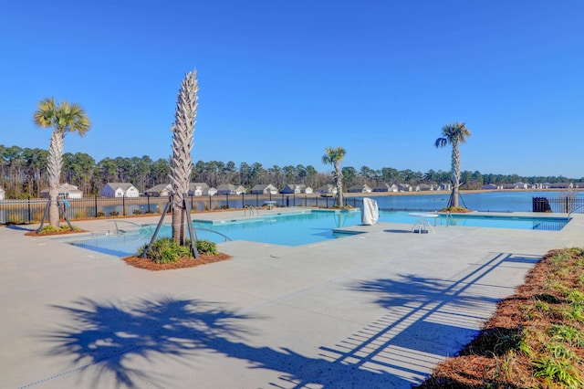 pool featuring a water view, fence, and a patio