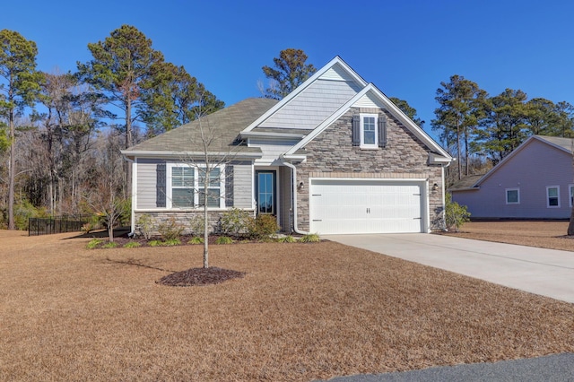 craftsman-style house with a garage, stone siding, and concrete driveway