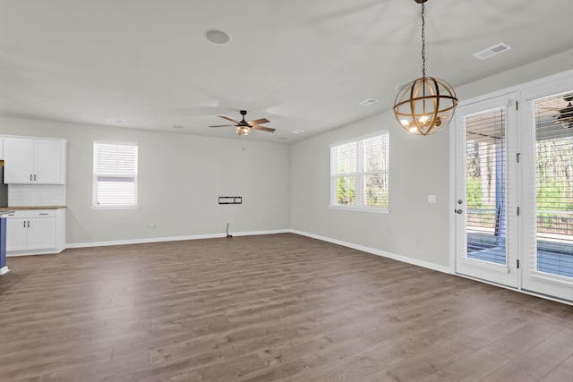 unfurnished living room featuring visible vents, wood finished floors, a wealth of natural light, and baseboards