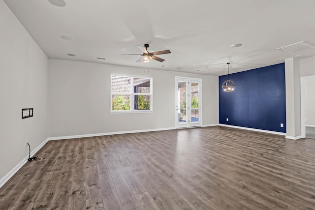 unfurnished room featuring visible vents, dark wood finished floors, baseboards, and ceiling fan with notable chandelier