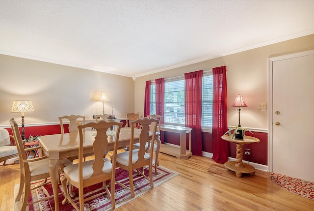 dining space featuring ornamental molding, light hardwood / wood-style floors, and a textured ceiling