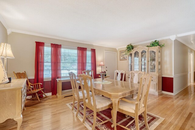 dining space with light wood-type flooring, crown molding, and a textured ceiling