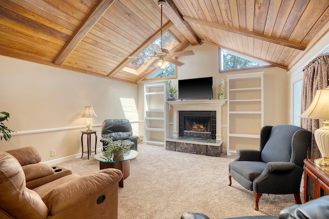 carpeted living room with wood ceiling, vaulted ceiling with skylight, ceiling fan, and a tile fireplace