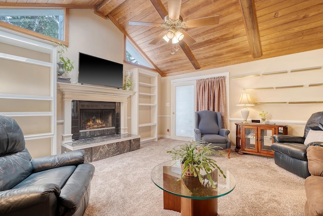 carpeted living room with a fireplace, wooden ceiling, built in shelves, ceiling fan, and beam ceiling