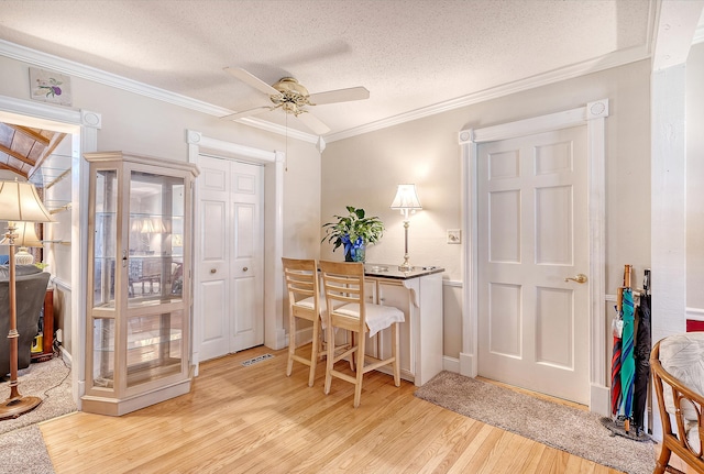 office space with ceiling fan, light hardwood / wood-style floors, crown molding, and a textured ceiling