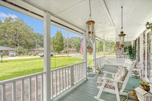 wooden terrace with a lawn and covered porch