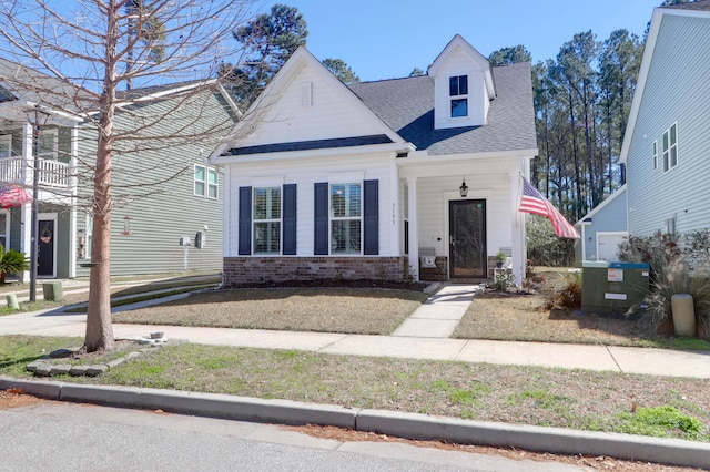 view of front of home with brick siding, a shingled roof, and cooling unit