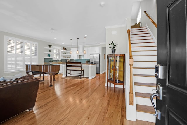 entrance foyer featuring ornamental molding, light wood-type flooring, recessed lighting, and stairs