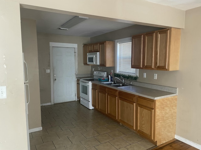 kitchen featuring white appliances, baseboards, light countertops, and a sink