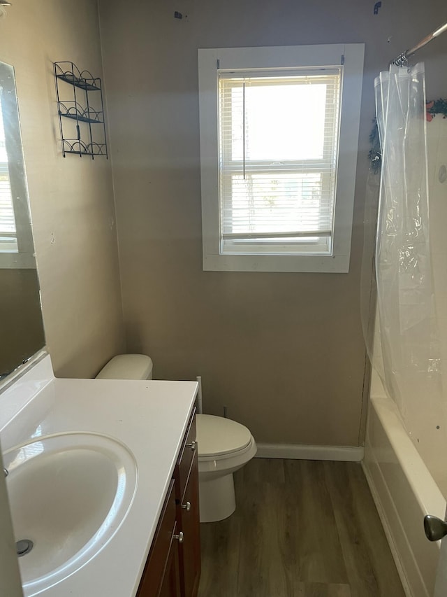 full bathroom featuring shower / tub combo, baseboards, toilet, wood finished floors, and vanity