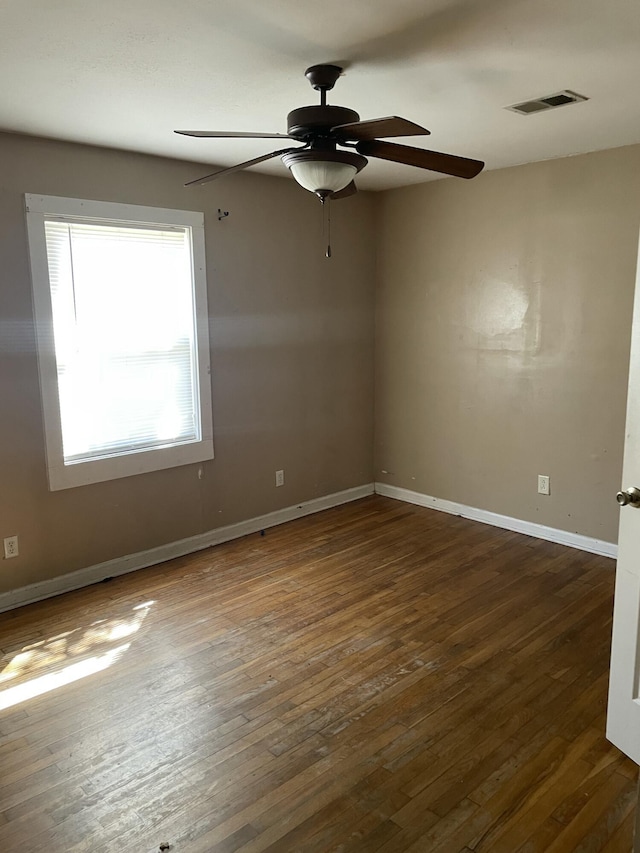 spare room featuring ceiling fan, hardwood / wood-style floors, visible vents, and baseboards